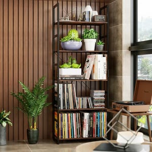Peut inclure: Une étagère en métal marron foncé et noir avec plusieurs étagères. Les étagères présentent des livres, des CD, des plantes en pot et des objets décoratifs. L'étagère est placée contre un mur en bois.
