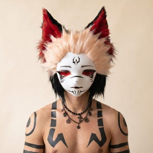 May include: A white fox mask with black markings and red eyes, featuring spiky blonde hair and tall, pointed ears with red and black fur. The mask is worn with a layered black beaded necklace featuring small charms, and black tribal-style body paint.