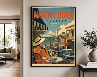 Puede incluir: Un póster de viaje enmarcado titulado VISIT MOUNT DORA FLORIDA LAKESIDE CHARM ALL YEAR. Muestra a una persona con sombrero de sol y vestido naranja sentada en una mesa de café con vistas a un lago, un faro, un coche antiguo y un barco de vapor.