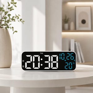 May include: A rectangular digital alarm clock with a black display and white frame. The screen shows the time 20:38 in large white digits, the date 10.26 in blue, the temperature 20 degrees Celsius in blue, and the day THU in white text.