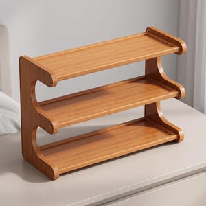 May include: A three-tier wooden shelf unit featuring a light brown wood grain finish. The structure consists of three horizontal rectangular shelves supported by two curved side panels that create an open, wave-like profile on each end.