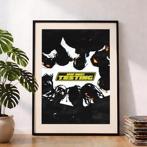 Puede incluir: Un póster enmarcado con la portada del álbum "Testing" de A$AP Rocky. La imagen muestra un grupo de personas con las cabezas juntas, con el título del álbum en un recuadro amarillo y verde. El póster está en un marco negro.