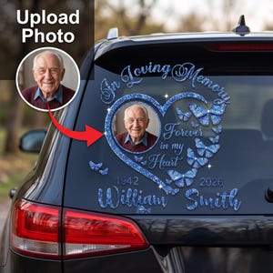 May include: A blue glitter memorial car decal featuring a heart-shaped frame with a portrait of an elderly man, butterflies, and the text In Loving Memory, Forever in my Heart, 1942, 2026, and the name William Smith applied to a vehicle rear window.