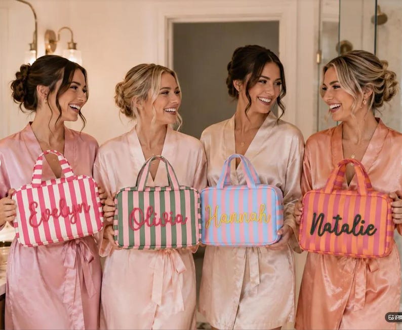 May include: Four rectangular cosmetic bags with top handles and vertical stripes. Each bag features a custom name embroidered on the front: Evelyn in pink, Olivia in red, Hannah in yellow, and Natalie in black. The bags are pink, green, blue, and orange.