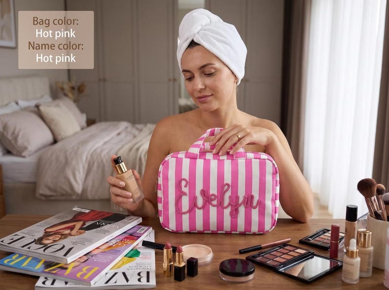 May include: A rectangular hot pink and white striped toiletry bag featuring the name Evelyn in hot pink script lettering on the front, with a top handle and a zipper closure, displayed alongside various makeup products and magazines.