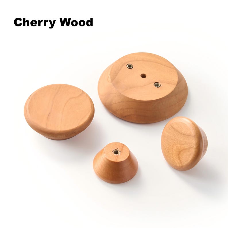 Op de afbeelding: Vier knoppen van kersenhout in verschillende maten met gladde, afgeronde oppervlakken. De tekst Cherry Wood is zichtbaar in de linkerbovenhoek. Sommige knoppen tonen metalen schroefdraadinzetstukken op hun platte onderzijden.