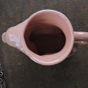 May include: A pink ceramic mug with a handle. The mug is empty and has a smooth, glossy finish.