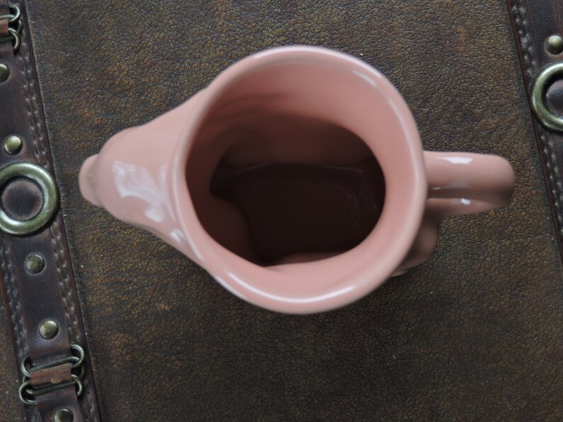 May include: A pink ceramic mug with a handle. The mug is empty and has a smooth, glossy finish.
