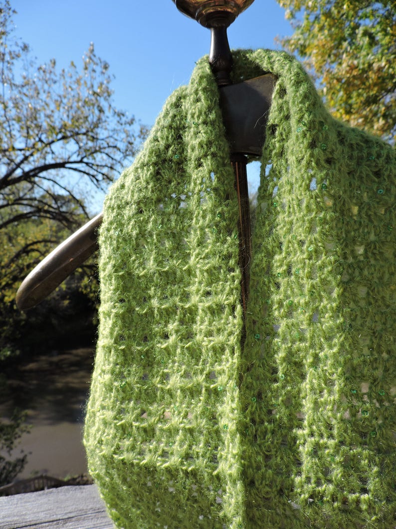 May include: A green crocheted scarf with a textured pattern and small green beads throughout.
