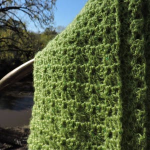 May include: A green crocheted shawl with a textured pattern and small green sequins.