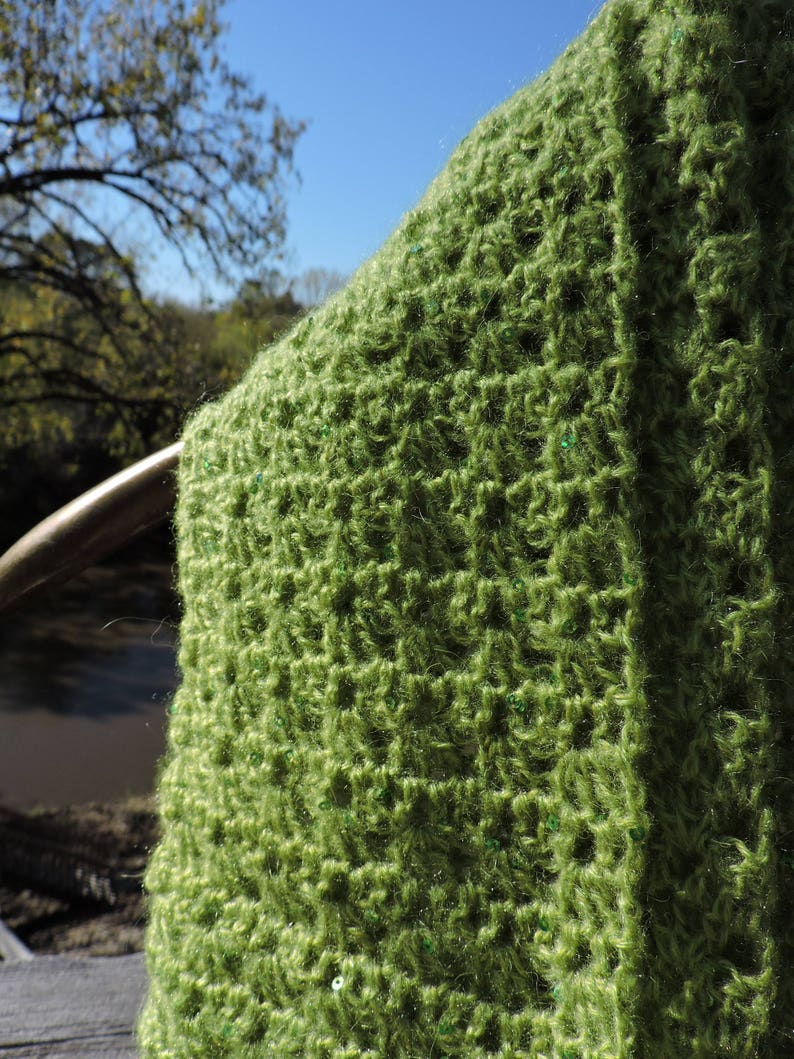 May include: A green crocheted shawl with a textured pattern and small green sequins.