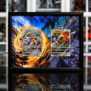 Pu&ograve; includere: Una cornice rettangolare nera contenente due carte collezionabili Pok&eacute;mon, Mewtwo VSTAR e Charizard VSTAR, montate su uno sfondo artistico vibrante con fiamme arancioni vorticose e texture rocciose scure e frastagliate dietro le carte.