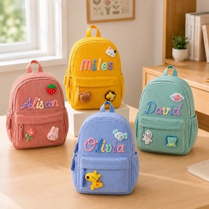 Può includere: Quattro zaini in velluto a coste nei colori rosa, giallo, blu e verde. Ogni zaino presenta un nome personalizzato con lettere colorate e varie piccole toppe in peluche come fragola, gatto, orso, leone, fiore, coniglio, elefante, astronauta e dinosauro.
