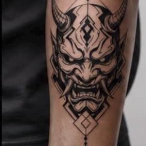 Peut inclure: Tatouage noir et blanc d'un masque Oni japonais avec des cornes, des dents pointues et des formes géométriques. Le tatouage est sur le bras d'une personne, mettant en valeur le travail de ligne et l'ombrage complexes.
