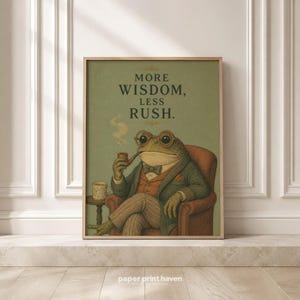 May include: A framed wall art print featuring an illustration of a toad wearing round glasses, a green jacket, and a bowtie, sitting in a chair while holding a smoking pipe. The text reads MORE WISDOM, LESS RUSH. A small cup sits on a side table.