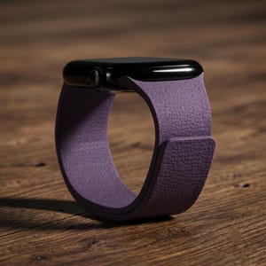 May include: A smartwatch with a black rectangular case and a textured purple silicone band. The band features a smooth, matte finish with a distinct pebbled grain pattern on the outer surface, secured by a simple overlapping strap design.
