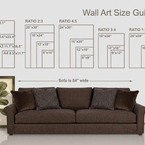 May include: A wall art size guide chart with text and rectangular outlines showing various dimensions in inches, positioned above a brown sofa that is 84 inches wide. To the left, a framed botanical print of a Ficus Lyrata plant is displayed.