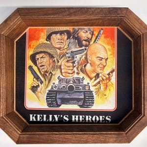 May include: A framed print of the film poster for Kelly's Heroes, featuring four soldiers and a tank against a fiery orange background. The wooden frame is octagonal with a dark brown finish. The text Kelly's Heroes is printed in white at the bottom.