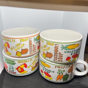 May include: A set of four white ceramic soup bowls featuring colorful illustrations of vegetables and poultry. The bowls are decorated with text labels including Chicken Soup, Onion Soup, Mushroom Soup, Vegetable Soup, Pea Soup, and Potato Soup.