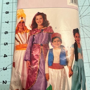 May include: A Butterick 3049 sewing pattern envelope featuring four children wearing various costumes. The costumes include a white and gold outfit with a turban, a purple dress with gold trim, a white and blue outfit with a red vest, and a teal two-piece set.