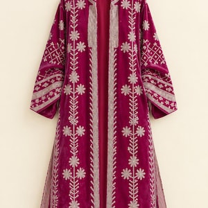 May include: A magenta velvet duster coat featuring long sleeves and an open front. The garment is decorated with intricate silver-toned floral and geometric embroidery along the placket, cuffs, and side panels, with striped fabric accents.