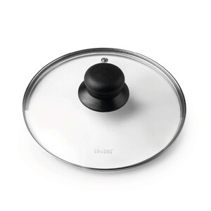 May include: A circular clear glass pot lid featuring a silver-toned metal rim and a central black knob handle. The glass surface displays the brand name ibili printed in small grey letters near the bottom edge of the lid's transparent surface.