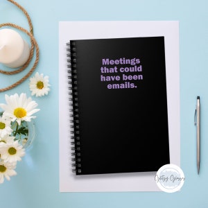 May include: Black spiral bound notebook with the text "Meetings that could have been emails." printed in purple on the front cover.
