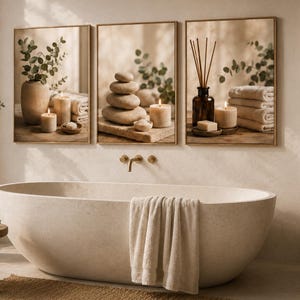 May include: A set of three framed wall art prints featuring spa-themed imagery. The prints display beige stone stacks, lit pillar candles, a brown glass bottle with reed diffusers, folded white towels, and green eucalyptus branches in a ceramic vase.