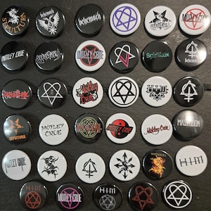 May include: A collection of thirty-six circular pin-back buttons featuring various band logos and symbols. The designs include logos for Motley Crue, HIM, Sepultura, Mastodon, and Spiritbox in black, white, red, and purple colour schemes.