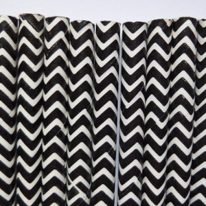 May include: A close-up of several black and white chevron patterned paper straws. The straws are arranged vertically against a white background. The zig-zag pattern is a classic design element.