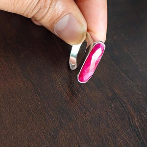 May include: A silver ring featuring a long, narrow, faceted hot pink gemstone set vertically. The ring has a smooth, polished metal band. The image includes the text OVR CREATIONS in the bottom left corner with a small circular logo.