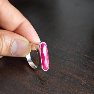 May include: A silver ring featuring a long, rectangular, faceted hot pink gemstone set vertically in a smooth metal bezel. The ring band is plain and polished silver. The text OVR CREATIONS is visible at the bottom of the image.