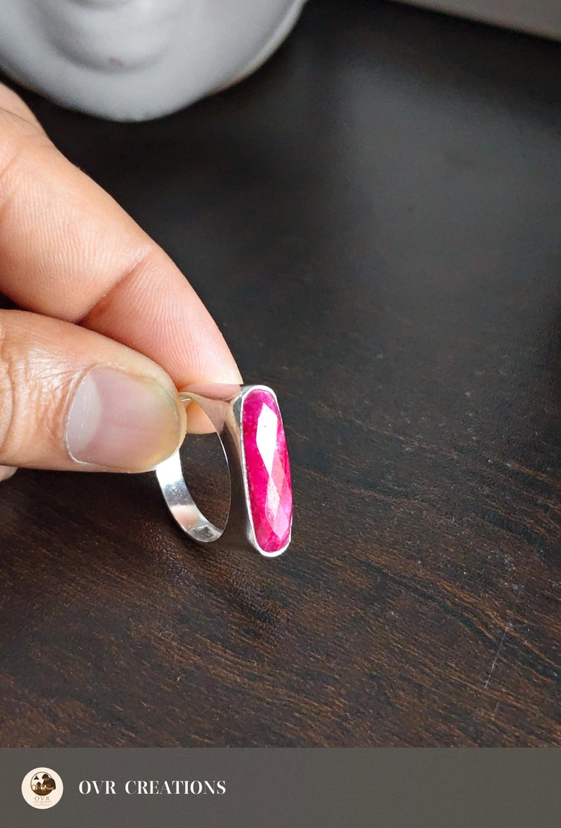May include: A silver ring featuring a long, rectangular, faceted hot pink gemstone set vertically in a smooth metal bezel. The ring band is plain and polished silver. The text OVR CREATIONS is visible at the bottom of the image.