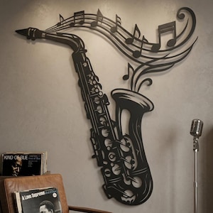 Pode incluir: Uma peça de arte de parede em metal preto em forma de saxofone com notas musicais fluindo da campainha. O design apresenta recortes intrincados que representam chaves e válvulas, criando a silhueta de um instrumento musical em movimento.