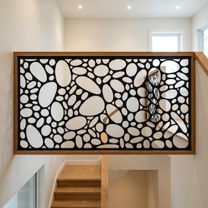 May include: A rectangular stair railing panel featuring a black metal frame with a laser-cut pattern of irregular, rounded pebble-like shapes. The panel is mounted within a light-toned wooden frame, positioned horizontally above a wooden staircase.