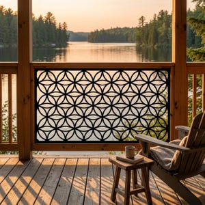 May include: A rectangular black metal privacy screen featuring a repeating geometric pattern of interlocking circles, installed as a railing panel on a wooden deck, providing a decorative barrier with a clear view of the lake and forest beyond.