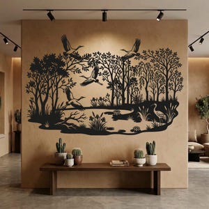 May include: A black wall decal featuring a detailed nature scene with multiple cranes in flight and standing among trees, reeds, and water lilies. The silhouette design depicts a serene landscape with birds and foliage, applied to a tan wall.