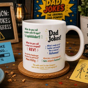 Puede incluir: Una taza de cerámica blanca con varios chistes de papá impresos en texto negro, verde, rojo y azul. La taza muestra múltiples juegos de palabras y preguntas, incluyendo "What do you call a spider with 10 eyes?" y "What's made out of leather and sounds like a sneeze?"