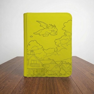 May include: A bright lime green rectangular binder featuring a line art illustration of a winged dragon flying above a suburban neighborhood with houses and clouds. The cover has stitched edges and a smooth, uniform texture throughout the surface.
