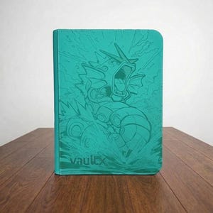 Può includere: Un raccoglitore per carte collezionabili color verde acqua con una grafica in rilievo di una creatura marina serpentiforme a bocca aperta. La copertina ha una superficie testurizzata e riporta il testo "vaultx" nell'angolo in basso a sinistra.