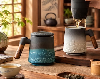 May include: Two ceramic tea mugs with wooden handles, one blue and black with a mountain and wave relief pattern, and one white and black with a similar relief pattern, featuring a removable black tea infuser basket for brewing loose leaf tea.