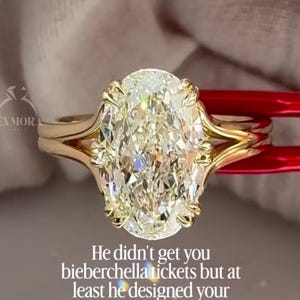 Peut inclure: Une bague en or avec une grande pierre centrale taille ovale fixée par huit griffes sur un anneau à tige fendue. L'image contient le texte 'SEXMORA' et 'He didn't get you bieberchella tickets but at least he designed your dream ring...'