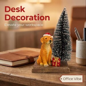 May include: A golden retriever figurine wearing a red and white Santa hat, positioned on a square wooden base next to a small, snow-dusted artificial pine tree and a miniature red gift box with a gold ribbon, all set on a wooden desk surface.