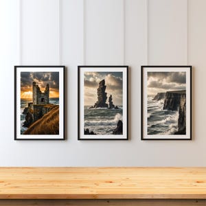 May include: Three framed wall art prints featuring coastal landscapes. The left print shows a stone ruin on a cliff at sunset. The center print displays jagged sea stacks in turbulent water. The right print depicts dark cliffs with crashing waves.