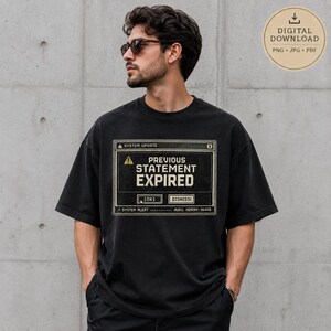 Puede incluir: Una camiseta negra de manga corta con un estampado gráfico de una ventana de actualización del sistema informático. El texto dice: SYSTEM UPDATE, PREVIOUS STATEMENT EXPIRED, OK, DISMISS, SYSTEM ALERT y AURIL MEMORY: 064KB. Incluye un icono de advertencia.