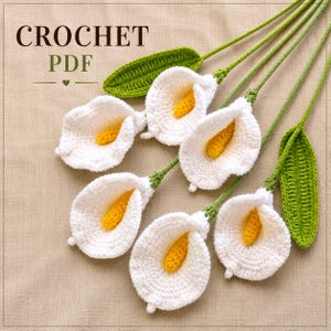 May include: A set of five handmade crochet calla lilies with white petals, yellow centers, and green stems and leaves. The text CROCHET PDF is visible in the upper left corner. The flowers are arranged in a cluster on a neutral fabric background.