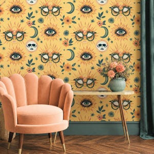 May include: Wallpaper featuring a repeating pattern of yellow suns wearing dark-rimmed glasses, crescent moons, and orange flowers on a mustard yellow background. The design includes stylized eyes and small star shapes scattered throughout the print.