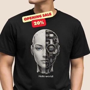 Könnte beinhalten: Ein schwarzes T-Shirt mit einer Grafik eines menschlich wirkenden Gesichts, das in der Mitte geteilt ist. Eine Seite zeigt eine glatte weiße Oberfläche, die andere Seite enthüllt komplexe mechanische Zahnräder und Schaltkreise. Darunter steht "Hello world!".