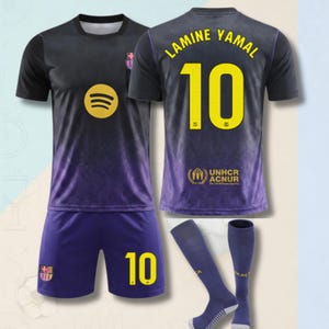 May include: A black and purple soccer jersey set featuring the name LAMINE YAMAL and the number 10 in yellow. The jersey includes a Spotify logo, the FC Barcelona crest, and the UNHCR ACNUR logo. The set includes matching shorts and socks.
