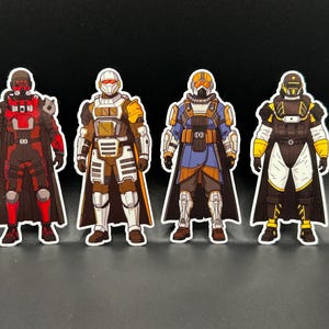 Pode incluir: Quatro autocolantes recortados com personagens blindadas em esquemas de cores distintos. O primeiro é vermelho e preto, o segundo branco e dourado, o terceiro azul e laranja, e o quarto preto e amarelo. Cada figura usa um capacete e uma capa.